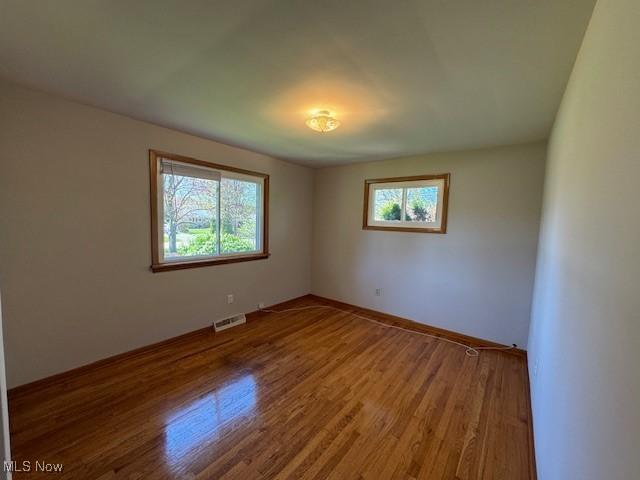 unfurnished room with visible vents, baseboards, and wood finished floors