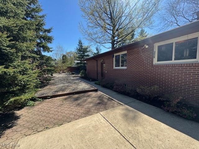 view of side of home with a patio area and brick siding