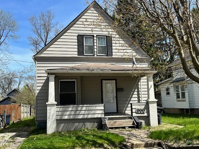 view of front of house with fence, a porch, and roof with shingles