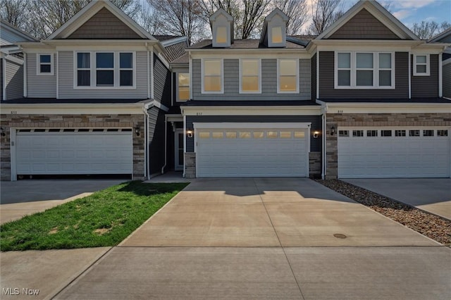view of property with an attached garage, concrete driveway, and stone siding