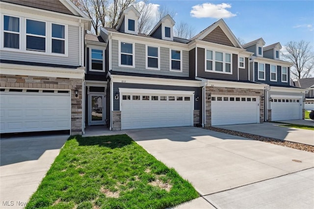 multi unit property featuring concrete driveway, an attached garage, and stone siding