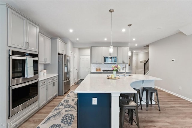 kitchen featuring a sink, gray cabinetry, stainless steel appliances, and light wood-type flooring