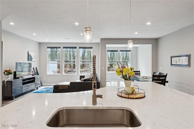kitchen with pendant lighting, light stone counters, recessed lighting, and open floor plan