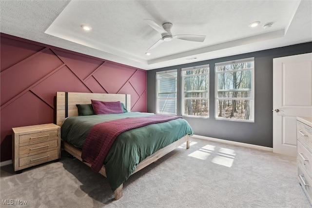 bedroom with recessed lighting, a tray ceiling, light carpet, and baseboards
