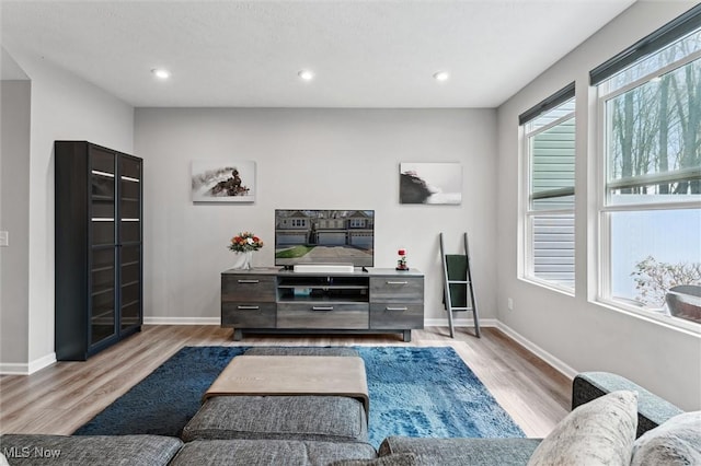 living area with baseboards, recessed lighting, and light wood finished floors