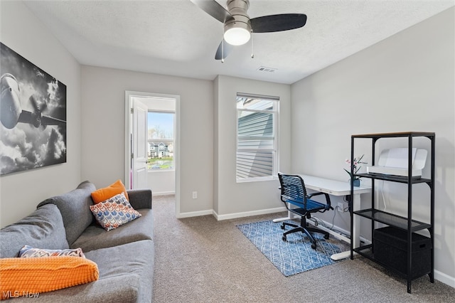 home office featuring ceiling fan, a textured ceiling, visible vents, baseboards, and carpet