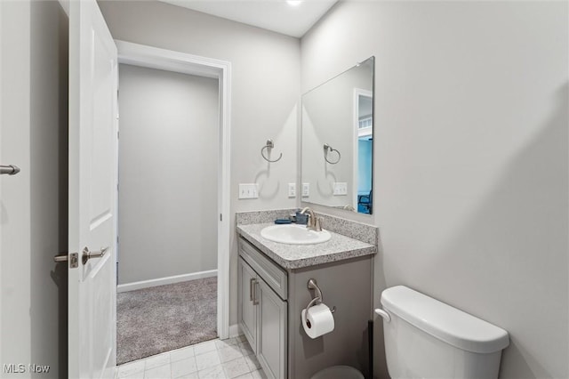 half bathroom with vanity, baseboards, and toilet