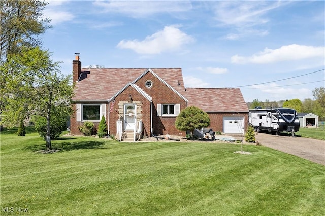 tudor home with aphalt driveway, a front yard, a chimney, brick siding, and an attached garage