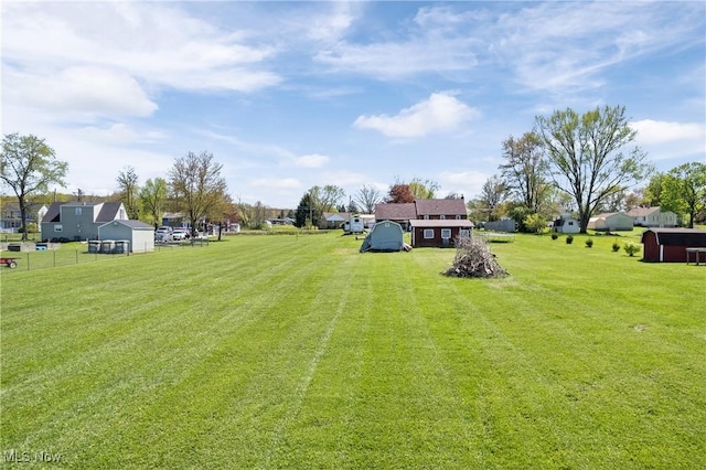 view of yard featuring a shed, an outbuilding, a residential view, and fence
