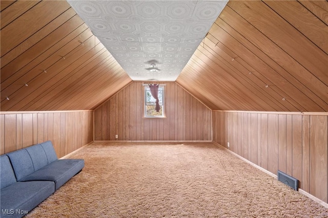 additional living space featuring carpet floors, baseboards, wood walls, and visible vents