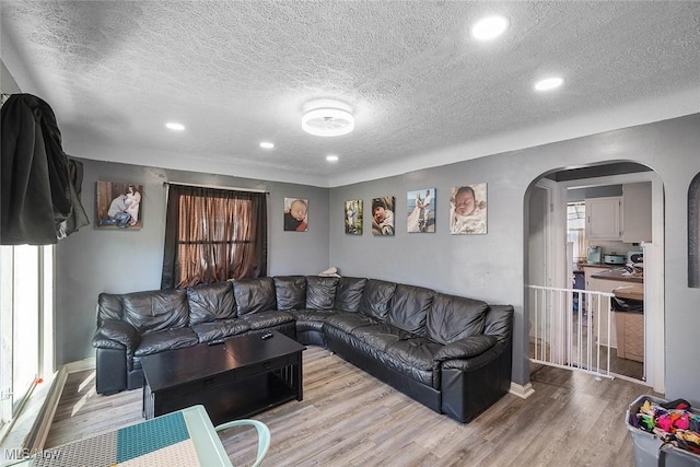 living area featuring arched walkways, recessed lighting, a textured ceiling, and wood finished floors