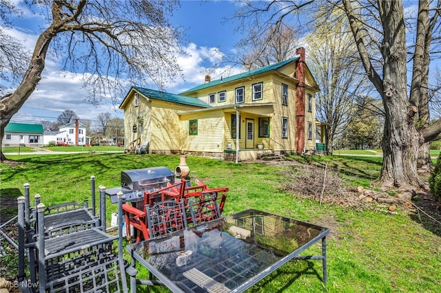 8935 S Main St, Windham, OH 44288 - rear view of property featuring a lawn, a chimney, and metal roof