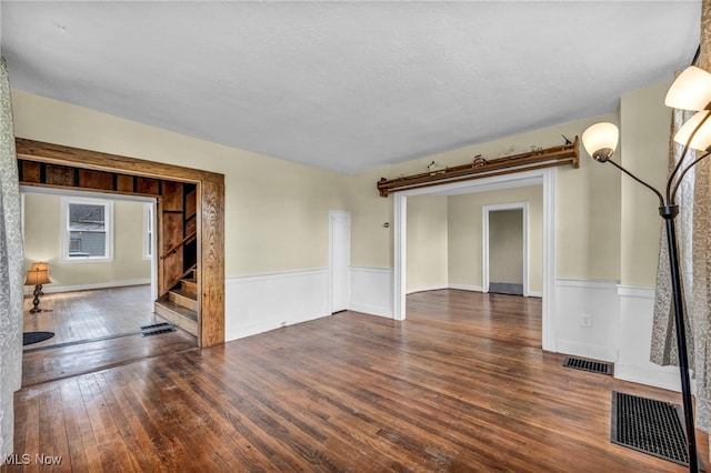 8935 S Main St, Windham, OH 44288 - unfurnished living room featuring visible vents, a wainscoted wall, and hardwood / wood-style floors