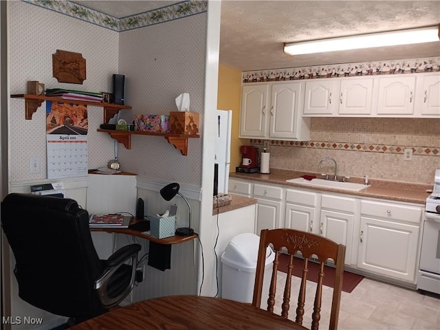 kitchen featuring a sink, open shelves, white cabinets, and wallpapered walls
