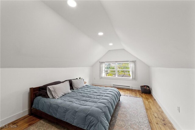 bedroom with vaulted ceiling, wood-type flooring, a baseboard heating unit, and recessed lighting