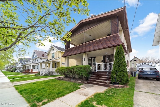 view of front of house with covered porch, a residential view, a shingled roof, and a front yard
