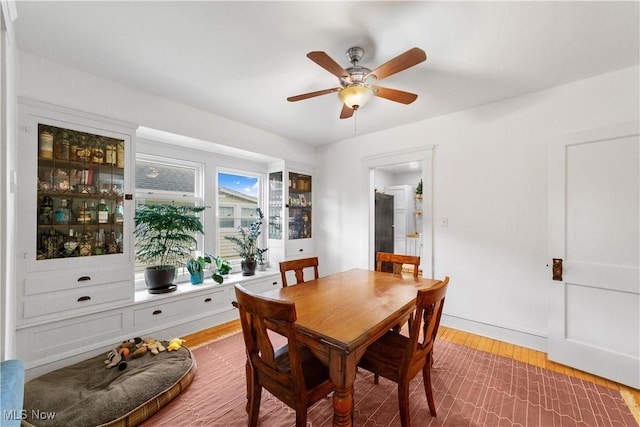 dining space with a ceiling fan and wood finished floors