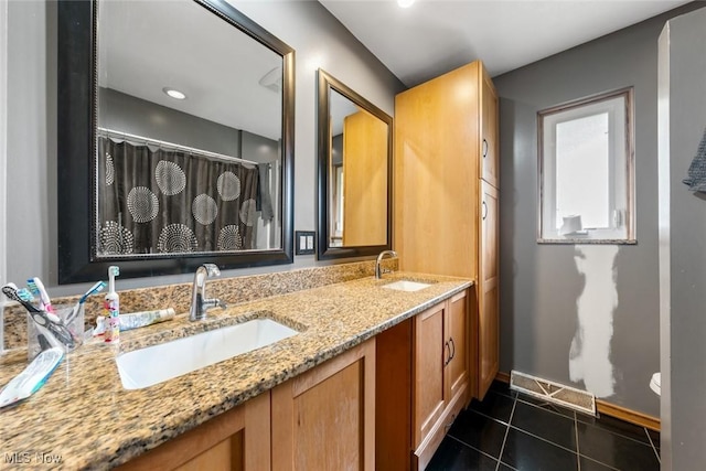 bathroom with baseboards, double vanity, tile patterned floors, and a sink