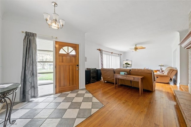 foyer entrance with ceiling fan with notable chandelier and light wood finished floors