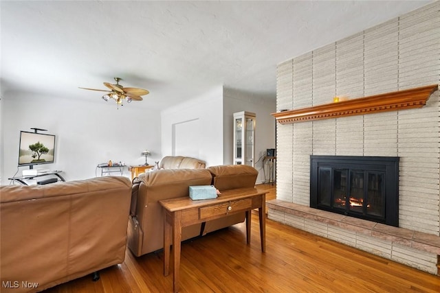 living room with ceiling fan, wood finished floors, and a fireplace