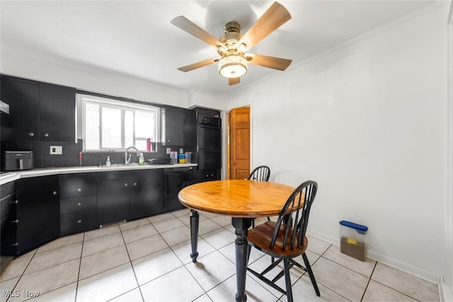 kitchen featuring light countertops, tasteful backsplash, dark cabinetry, a sink, and black appliances