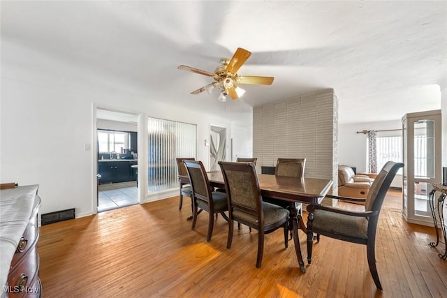 dining room with baseboards, a ceiling fan, light wood-style flooring, and visible vents