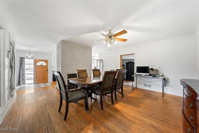 dining area featuring baseboards, ceiling fan with notable chandelier, light wood finished floors, and visible vents