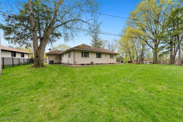 rear view of house with fence and a yard