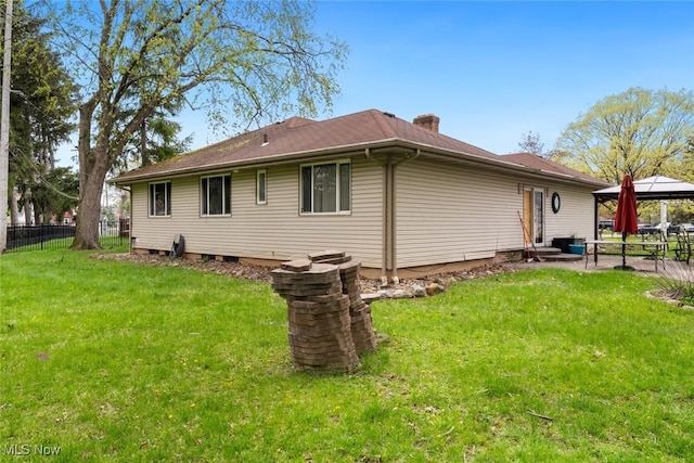 back of house with fence, a yard, a gazebo, and a chimney