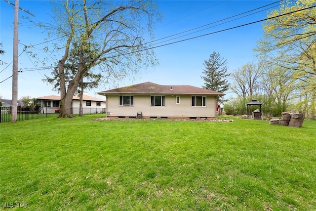 rear view of property featuring fence and a yard