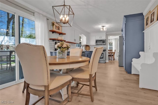 dining room with crown molding, light wood-style floors, and a notable chandelier