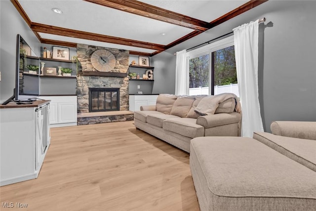living room with a stone fireplace, light wood finished floors, and beam ceiling