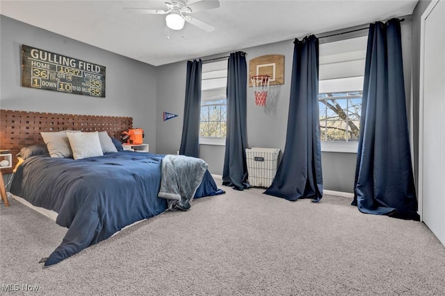bedroom featuring carpet flooring, radiator, a ceiling fan, and multiple windows
