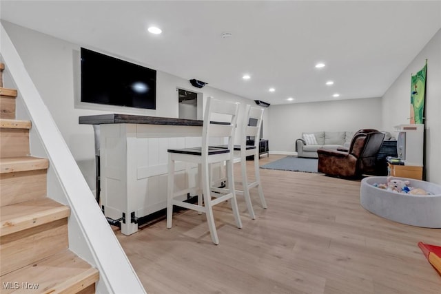 interior space featuring recessed lighting, light wood-style flooring, baseboards, and a bar