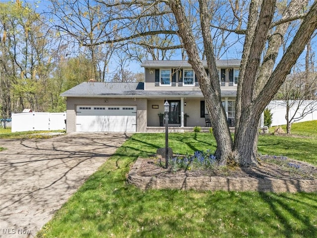 traditional home featuring a garage, fence, a front yard, brick siding, and driveway