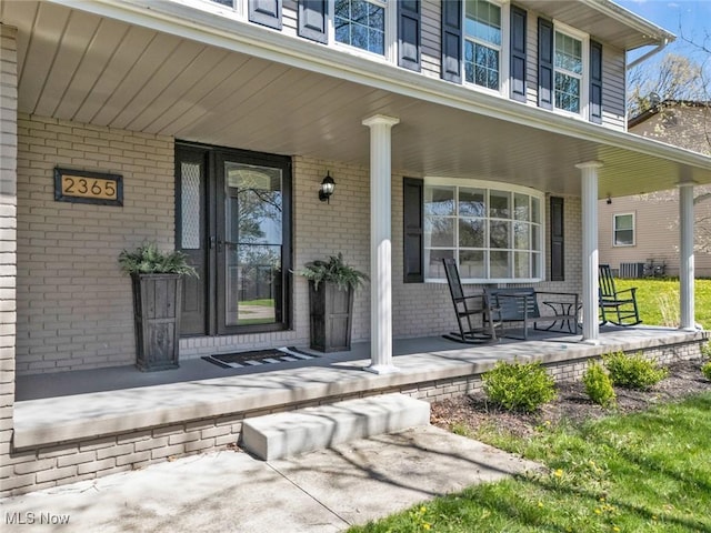 doorway to property featuring brick siding and covered porch