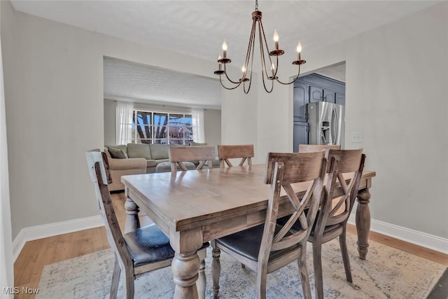 dining room featuring baseboards, an inviting chandelier, and light wood-type flooring