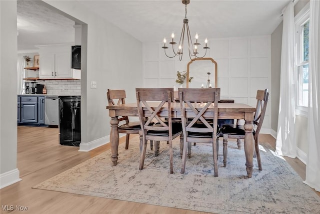 dining area featuring an inviting chandelier, baseboards, and light wood-style flooring