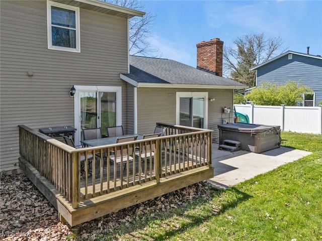 rear view of property featuring fence, a hot tub, a wooden deck, a chimney, and a yard