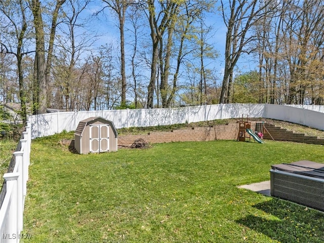 view of yard featuring a storage shed, an outdoor structure, a playground, and a fenced backyard