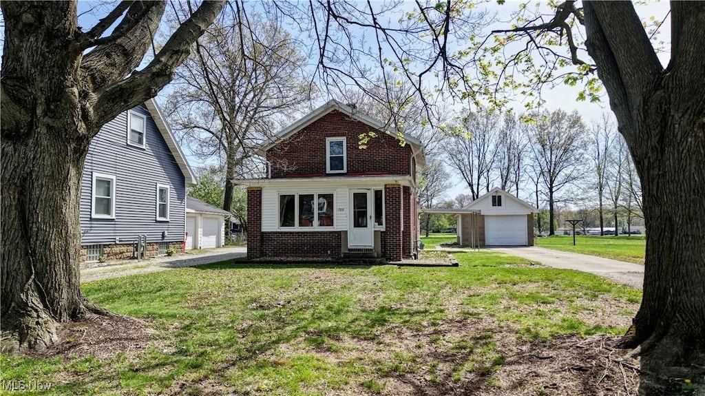 view of front of house with brick siding, a detached garage, a front yard, entry steps, and an outbuilding