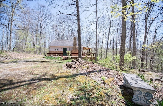 exterior space with a view of trees and a wooden deck