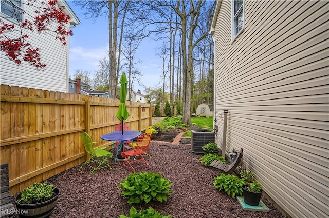 view of yard with central AC unit, fence, an outbuilding, and a shed