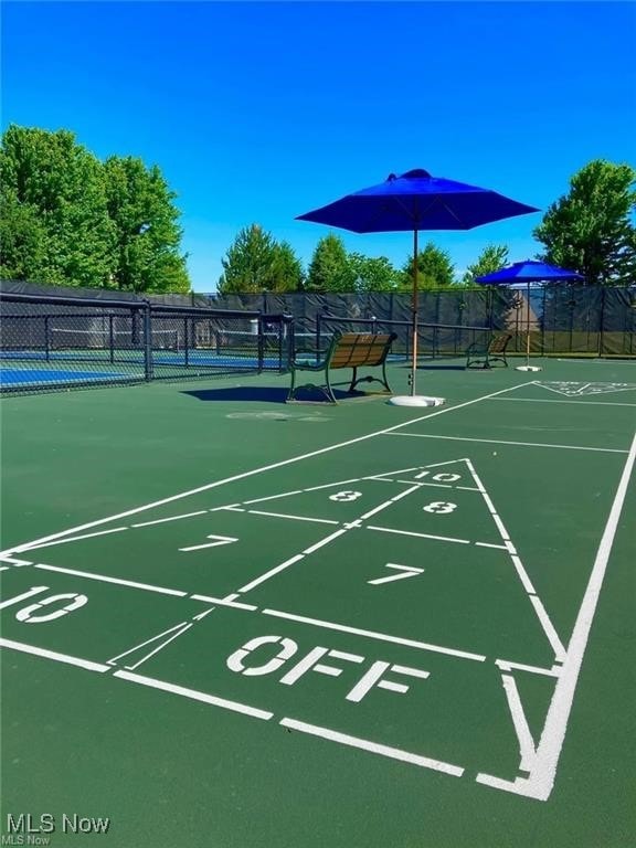 surrounding community with fence, shuffleboard, and a tennis court