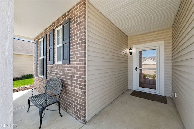 entrance to property with covered porch and brick siding
