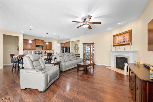 living area featuring a ceiling fan, baseboards, a fireplace with flush hearth, recessed lighting, and dark wood-style floors