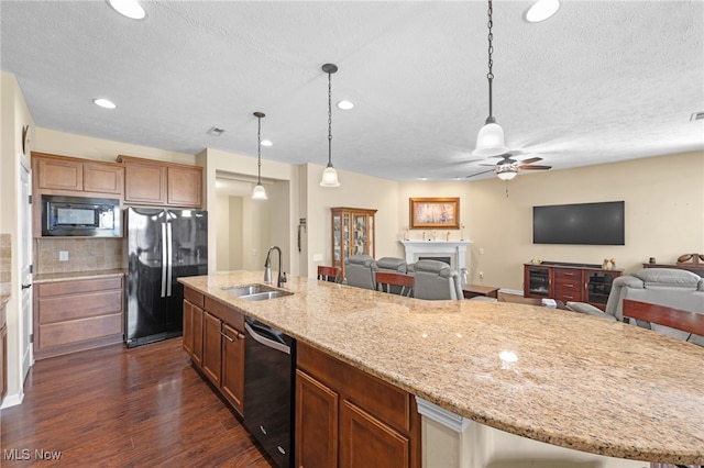 kitchen with a fireplace, dark wood-style floors, a textured ceiling, a sink, and black appliances