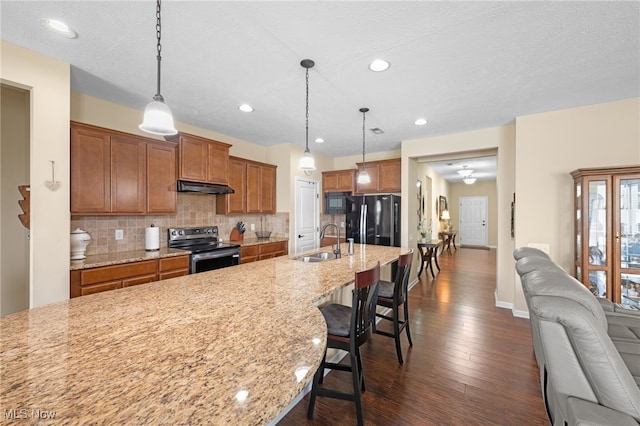 kitchen featuring backsplash, a sink, black appliances, open floor plan, and under cabinet range hood