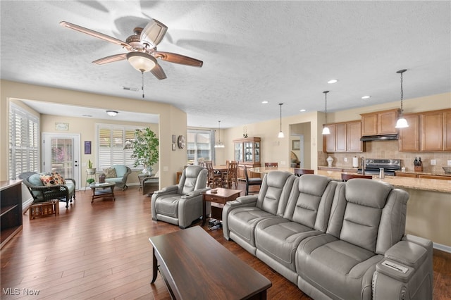 living area featuring recessed lighting, a ceiling fan, a textured ceiling, and dark wood finished floors