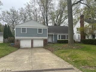 split level home featuring a garage, a front lawn, and driveway